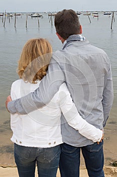 Back view of a couple hugging and watching the sea