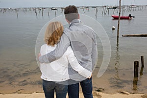 Back view of a couple hugging and watching the sea