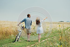 back view of couple with retro bicycle in summer field