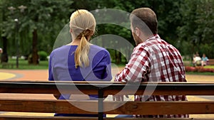 Back view of couple sitting on park bench, spending time together, conversation