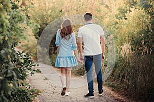 Back view couple walking away in the field, view of couple holding hands