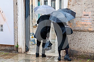 Back view of couple wandering in the rain in Venice Italy.