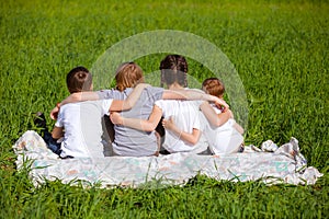 Back view of cute kids seated on green grass