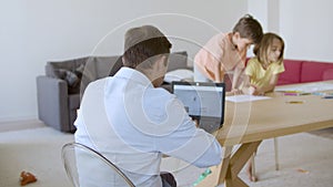 Back view of dad working on laptop computer at home