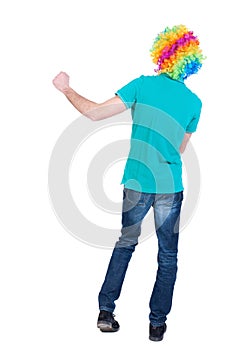 Back view of dancing young beautiful man in clown wig.