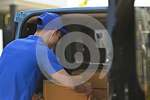 Back view of delivery men unloading cardboard boxes from cargo van. Delivery service, delivery home and shipping concept