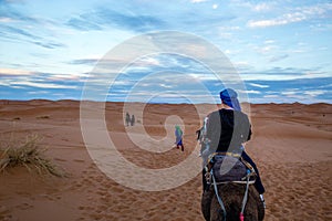 Back view of a deserter on a horse with a few deserters in the front in desert under a blue sky photo