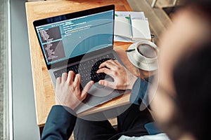 Back view of developer programmer freelancer working on project in cafe. Blurred background