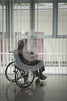 Back view of disabled senior man reads a newspaper