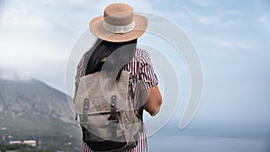 Back view elegant travel woman in straw hat and backpack admiring amazing sea scenery mountain peak