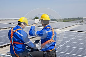 Back view of engineer checking on solar panel on the factory rooftop