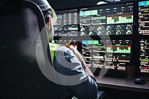 Back view on engineer operator and computer screens with modern following production system Industry 4.0 Head engineer of factory