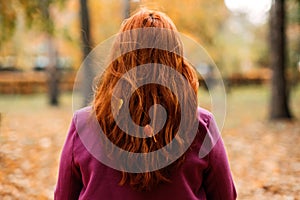 Back view faceless portrait of red-haired girl with fall leaves in hair. Autumn Portrait of happy woman