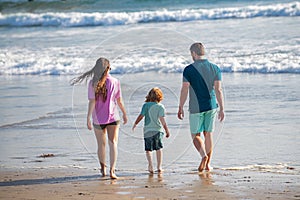 Back view of family on the beach. People having fun on summer vacation. Father, mother and child holding hands against