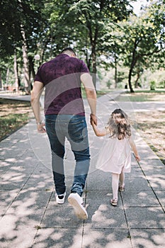 Back view of father and daughter walking