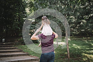 Back view of father having daughter on his shoulders