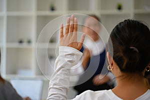 Back view of female college student raising hand to answering a question during lecture