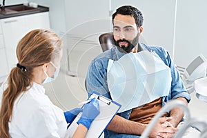 Back view of the female dentist in dental office talking with male patient