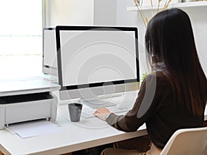 Back view of female office worker working with computer device in office room