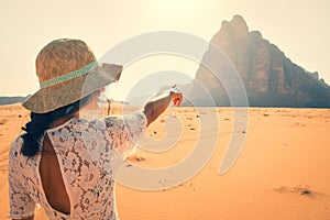 Back view female tourist stand watch point finger to seven pillars of wisdom monument in wadi rum desert-famous nature reserve in