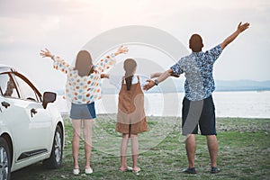 Back view of Freedom family father, mother and daughter having fun on a tropical beach and a car on the sider. Family vacation