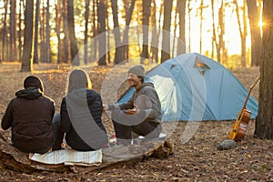 Back view of friends camping in autumn forest