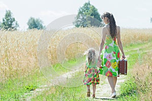 Back view full length portrait of walking mother and her little daughter on rural country road