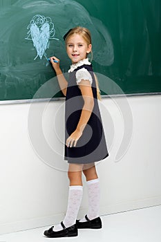 Back view of girl drawing with chalk on blackboard