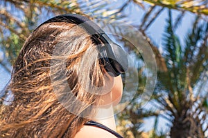 Back view on the girl in the headphones listening music  walks in the palm forest. Seychelles islands.