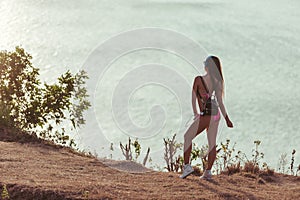 back view of girl in headphones pink bikini and bag looking at sea