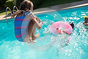 Back view of girl in swimsuit jumping into swimming pool