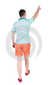 Back view of going handsome man in shorts. walking young guy