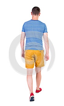 Back view of going handsome man in shorts. walking young guy