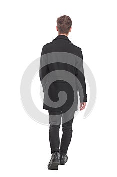 Back view of going handsome young business man in coat walking away.