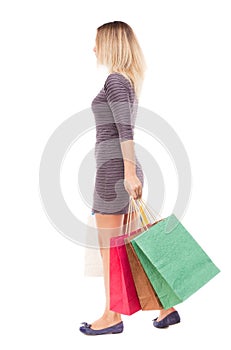Back view of going woman with shopping bags
