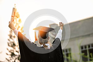 Back of view Graduate put hands up and celebrating with certificate in her hand and so proud and happiness in Commencement day