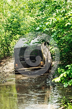 Back view of green russian off-road utility vehicle UAZ Hunter broke down, jammed on dirty road in forest among trees.