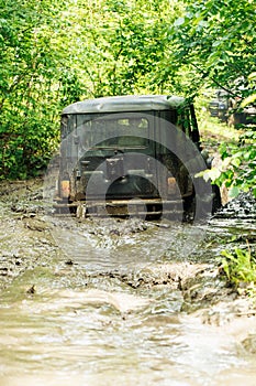 Back view of green russian off-road utility vehicle UAZ Hunter broke down, jammed on dirty road in forest among trees.