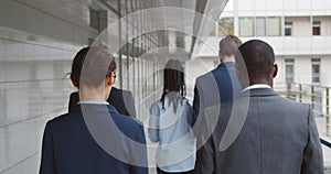 Back view of group of successful business people walking together outside business center