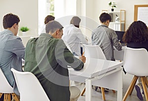 Back view of a group of young students writing during a lesson in the classroom.