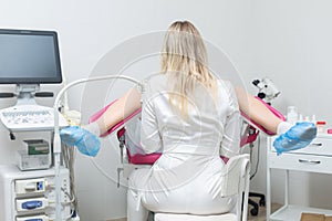 Back view of a gynecologist conducting a routine examination of a girl on a gynecological chair using modern medical