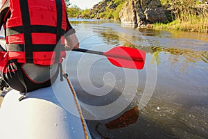 Back view of a hand with red paddle rafting on the river