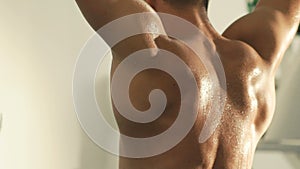 Back view of handsome deliquescent bodybuilder trains on workout equipment