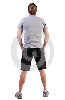 Back view of handsome man in t-shirt and shorts looking up