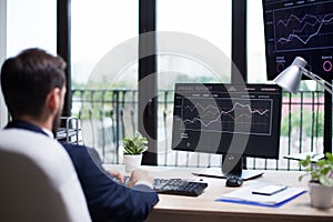 Back view of handsome young bearded business man typing on his computer