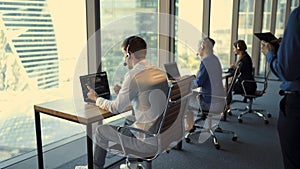 Back view of handsome young businessman and beautiful business women in headsets working in office