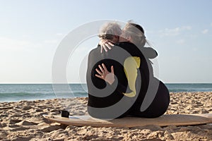 Back view of happy aged couple kissing on surfboard