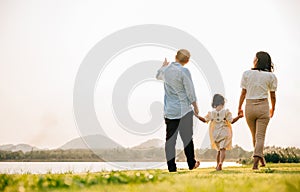 Back view of Happy Asian family walking and playing together in a scenic garden