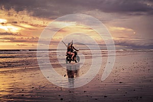 back view of happy couple riding motorcycle on ocean