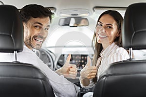 Back view happy couple showing high five, sitting in car